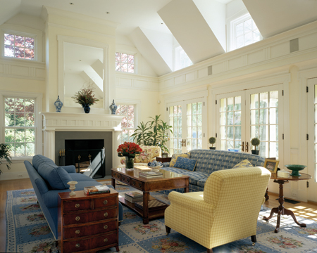The one-and-a-half-story family room shares an open space with the kitchen. It features two levels of windows and French doors, as well as a Classically-detailed fireplace. 