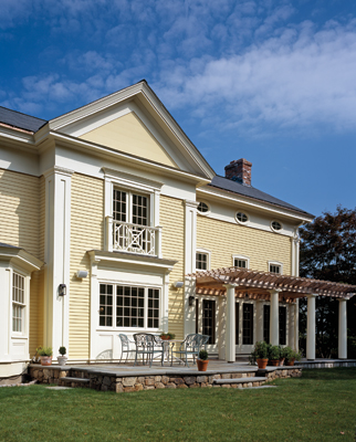 The rear elevation is detailed to match the front facade, but features a centered main gable, pergola and three sets of French doors that lead to a bluestone terrace. 